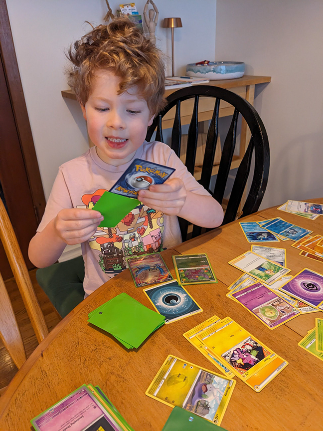 Casey happily sleeves his Pokémon card collection